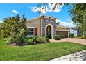 Inviting home exterior featuring a stone accent wall, manicured landscaping, and a two-car garage at 6909 Crestpoint Dr, Apollo Beach, FL 33572