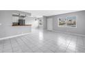 Open living room with white tile flooring, natural lighting, and an eat-in kitchen at 8039 Garden Dr # 105, Seminole, FL 33777