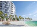 Beautiful beachfront featuring lounge chairs and cabanas by a modern condo building at 805 S Gulfview Blvd # 304A, Clearwater, FL 33767