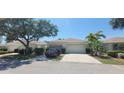 Exterior view of a well-maintained villa featuring a 2-car garage, tropical landscaping, and a paved driveway at 834 Tremont Greens Ln # 137, Sun City Center, FL 33573