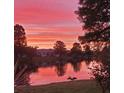 Scenic community lake view at sunset; red, orange, and pink hues illuminate the landscape and the lake's reflective surface at 834 Tremont Greens Ln # 137, Sun City Center, FL 33573
