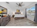 Bright main bedroom boasts a ceiling fan, a large window with gray curtains and sleek, modern wood flooring at 9647 Summers Cay Cir, Thonotosassa, FL 33592