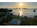 A golden sunrise over a swimming pool with palm trees and a view of the bay at 100 Oakmont Ln # 802, Belleair, FL 33756