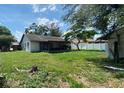 Spacious backyard featuring lush lawn, screened-in porch, white vinyl fencing, and large trees at 13603 Red Birch Pl, Tampa, FL 33625