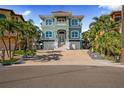 Charming two-story home with a two-car garage, meticulously manicured lawn, and tropical palm trees at 16365 Redington Dr, Redington Beach, FL 33708