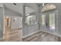 Inviting foyer with light wood-look floors, arched doorways, half wall and natural light streaming through the french doors at 16367 Ashington Park Dr, Tampa, FL 33647