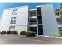 Three-story condo building with exterior access to units, mature landscaping and asphalt parking lot on a sunny day at 1859 Shore S Dr # 202, South Pasadena, FL 33707
