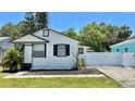 Charming single-Gathering home featuring a fresh white exterior, black trim, and an inviting, manicured front yard at 2219 Thrace St, Tampa, FL 33605