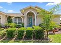 Attractive home entrance with a colorful door, manicured bushes, and a vibrant flowerbed at 22852 Fern Ct, Land O Lakes, FL 34639