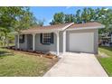 Beautiful house featuring lush lawn, attached garage, landscaping, and a freshly painted facade at 2613 E 113Th Ave, Tampa, FL 33612