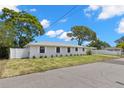 Eye-level street view of single story home with mature trees and a well-maintained front yard and white fence at 2907 W Tyson Ave, Tampa, FL 33611