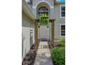 Inviting front entrance with a decorative pergola and lush hanging plants creating a warm and welcoming ambiance at 31747 Loch Aline Dr, Wesley Chapel, FL 33545