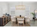 Bright dining room features a modern chandelier, wainscoting, and neutral tones creating an elegant atmosphere at 4345 Cadence Loop, Land O Lakes, FL 34638