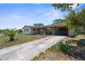 Quaint single-story home featuring an extended driveway and attached carport, with mature trees at 4499 Collins Rd, Spring Hill, FL 34606