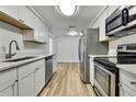 Modern kitchen featuring stainless steel appliances, light wood floors, and crisp white cabinetry at 5053 Lofton Dr, New Port Richey, FL 34652