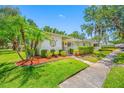 Landscaped front yard featuring palm trees and a decorative tree sculpture, adding curb appeal at 70 Cypress Pl, Oldsmar, FL 34677