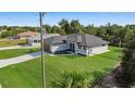 Aerial view of a modern single-story home with a manicured lawn and an elegant brick-paved driveway at 7054 Rosemont Dr, Englewood, FL 34224