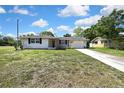 Exterior view of a charming single Gathering home with green lawn and blue skies at 7810 Pineapple Ln, Port Richey, FL 34668