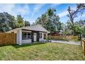 Inviting one-story house with a freshly cut lawn, surrounded by mature trees and a newly installed fence at 8603 N 9Th St, Tampa, FL 33604