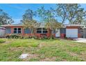 Charming single-story home with a well-manicured lawn, colorful flowers, and a cozy bench in front at 11348 59Th Ter, Seminole, FL 33772