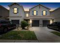 Charming two-story townhome at dusk with garage, manicured lawn, and stone accents at 12353 Bayou Flats Ln, Tampa, FL 33635