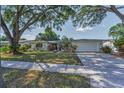 Inviting one-story home with an attached garage, complemented by a green lawn and mature trees at 1766 Hitching Post Ln, Dunedin, FL 34698