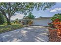 Inviting one-story home with an attached garage, complemented by a green lawn and mature trees at 1766 Hitching Post Ln, Dunedin, FL 34698