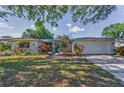 Charming single-story home featuring a well-maintained lawn and colorful landscaping, creating a welcoming curb appeal at 1766 Hitching Post Ln, Dunedin, FL 34698