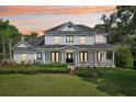 Stately two-story home at sunset showcasing a charming wrap-around porch and meticulous landscaping at 19803 Prince Benjamin Dr, Lutz, FL 33549