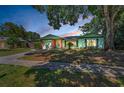 Beautiful one-story home featuring colorful evening skies, green siding, and a well-manicured lawn at 2212 Portside Psge, Palm Harbor, FL 34685