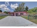 Charming pink one-story home featuring a covered carport, manicured lawn, and mature landscaping at 3104 W Powhatan Ave, Tampa, FL 33614