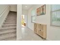 Bright entryway featuring tile floors, staircase, and stylish storage cabinet at 3228 Bryant Park Dr, New Port Richey, FL 34655