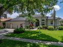 Traditional-style home featuring a well-manicured lawn, mature trees, and a spacious three-car garage at 3909 Valrico Grove Dr, Valrico, FL 33594