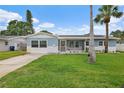 Charming blue single-story home featuring a well-manicured lawn and complemented by two palm trees at 4230 Indianapolis Ne St, St Petersburg, FL 33703