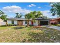 Charming single-story home with stone accents, a red door, fresh landscaping, and a dark garage door at 622 Cedar Grove Dr, Brandon, FL 33511