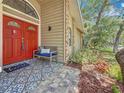 Inviting front porch with a vibrant red door, decorative tile flooring, and comfortable seating area at 66 Bay Woods Dr, Safety Harbor, FL 34695