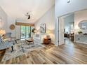Bright living room with vaulted ceilings, wood-look tile flooring, and a sliding glass door to the outdoors at 66 Bay Woods Dr, Safety Harbor, FL 34695