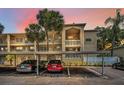Condominium building with covered parking, multiple stories, balconies, and well manicured grounds during a colorful sunset at 920 Virginia St # 109, Dunedin, FL 34698