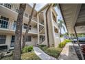 Condo building featuring multiple stories, balconies, beige stucco, stairs, lush landscaping, and sidewalk at 920 Virginia St # 109, Dunedin, FL 34698