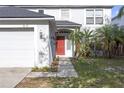 A close-up of a red front door with storm door, sidelight, and manicured yard at 10337 River Bream Dr, Riverview, FL 33569