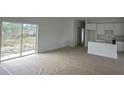 Spacious living room with sliding glass doors, connected to a kitchen with white cabinets and a breakfast bar at 11369 Gulfstream Blvd, Port Charlotte, FL 33981