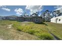 New construction home with a gray exterior and large windows surrounded by a grassy yard at 12047 Henley Ave, Port Charlotte, FL 33981