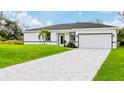 Beautiful single-story home with a well-manicured lawn, palm tree, and modern driveway leading to a two-car garage at 13266 Drysdale Ave, Port Charlotte, FL 33981