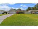 Charming single-story home featuring a well-manicured lawn, a red front door, and a gray driveway at 1546 69Th S Pl, St Petersburg, FL 33705