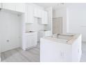 The bright kitchen is under construction, with white cabinets, an island frame, and laminate flooring at 16134 Libourn Ave, Port Charlotte, FL 33954