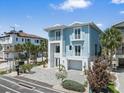 Beautiful two-story home featuring blue siding, white trim, balconies, and a paved driveway with lush landscaping at 2 Gulf Blvd, Indian Rocks Beach, FL 33785
