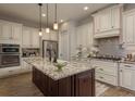 Spacious kitchen features an island with a granite countertop, stainless steel appliances, and custom cabinetry at 4583 Barletta Ct, Wesley Chapel, FL 33543