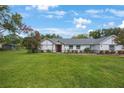 Beautifully maintained home features a lush green lawn, mature landscaping, and a welcoming red front door at 5933 Carina Trce, Wesley Chapel, FL 33545