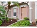 Townhouse exterior with pink door and shutters, surrounded by lush landscaping at 6109 Bayside Key Dr, Tampa, FL 33615