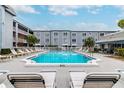 Community pool with lounge chairs surrounded by lush landscaping and multi-story building at 701 Poinsettia Rd # 340, Belleair, FL 33756
